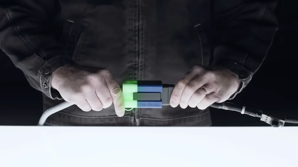 Close-up of two hands connecting a glowing industrial cable