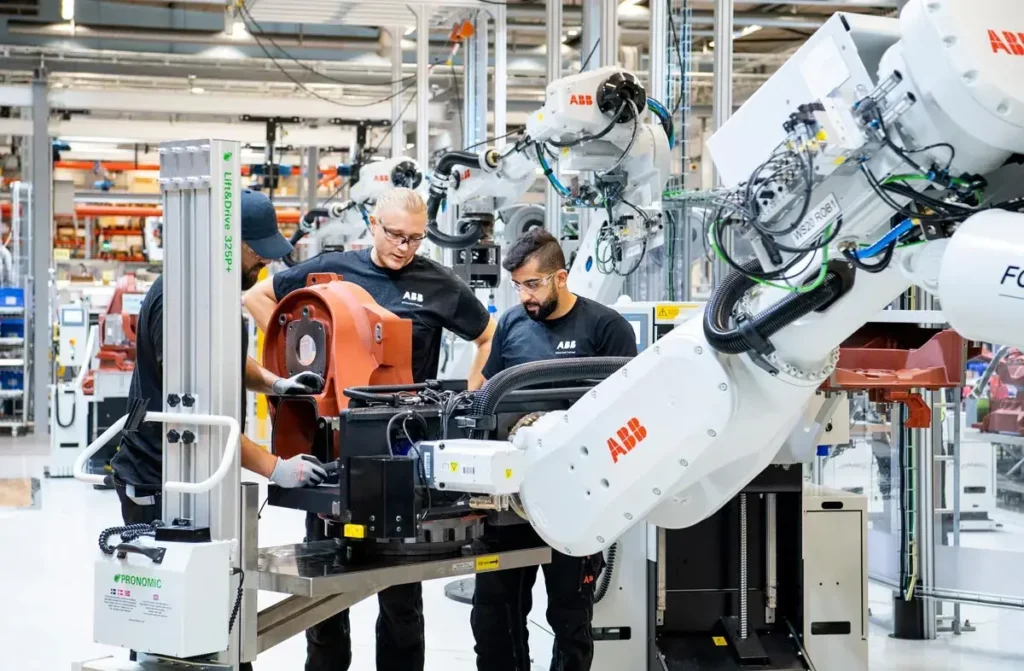 Technicians in a modern factory with robot arms with ABB logos