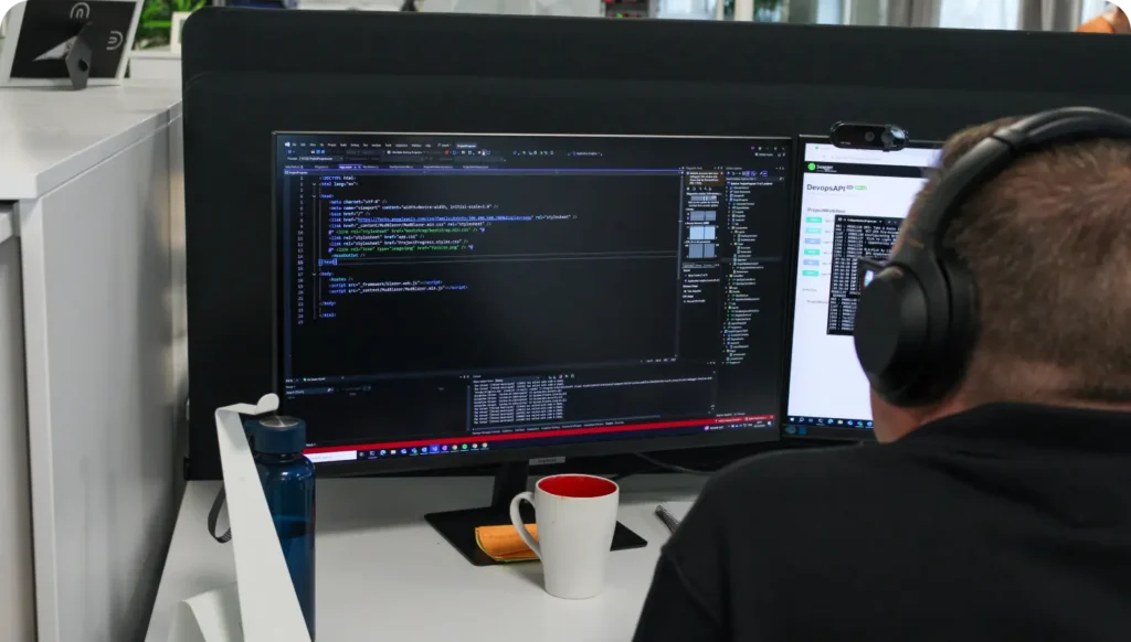Close-up of man with headphones looking at a computer screen with lines of code