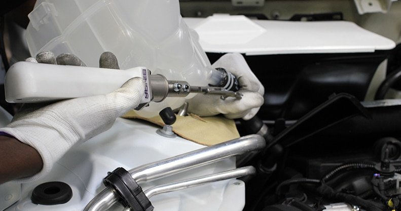 Close-up of hands with white gloves holding a Binar tool