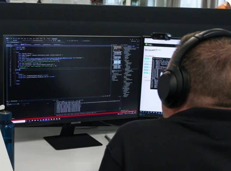 Man with headphones looking at a computer screen with lines of code